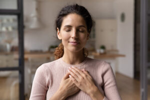 Calm young woman hold hands on chest celebrating valentine's day and mental health - Amend Treatment